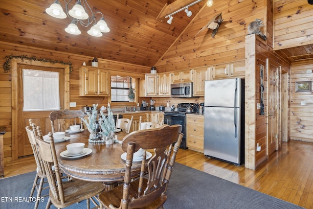 dining room featuring wood walls, rail lighting, wooden ceiling, a notable chandelier, and light wood-style flooring