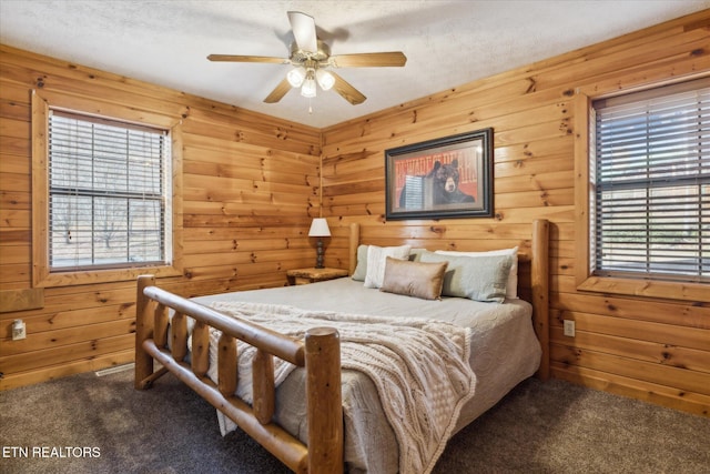 carpeted bedroom featuring multiple windows, wood walls, and a textured ceiling