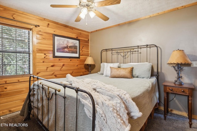 carpeted bedroom featuring visible vents, ceiling fan, and wooden walls
