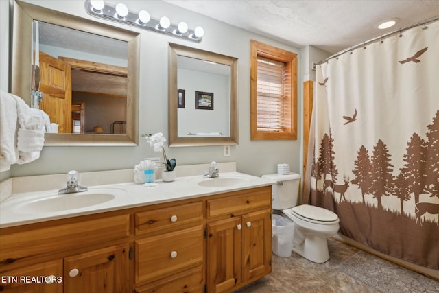 bathroom with double vanity, toilet, a textured ceiling, and a sink