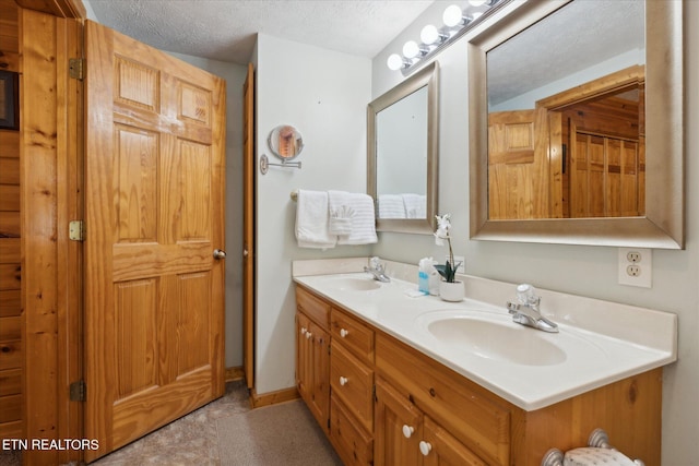 bathroom featuring double vanity, a textured ceiling, and a sink