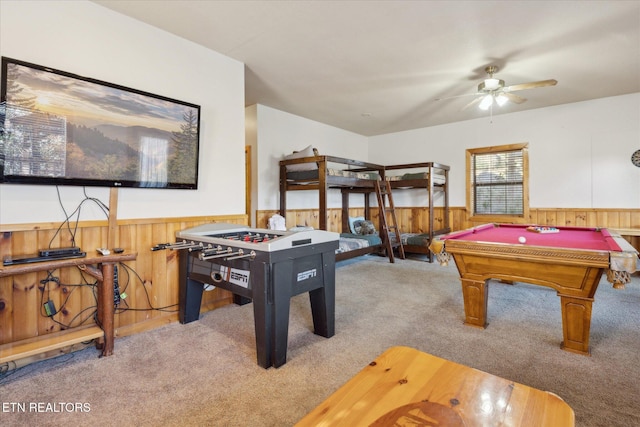 game room featuring carpet floors, a ceiling fan, wooden walls, and a wainscoted wall