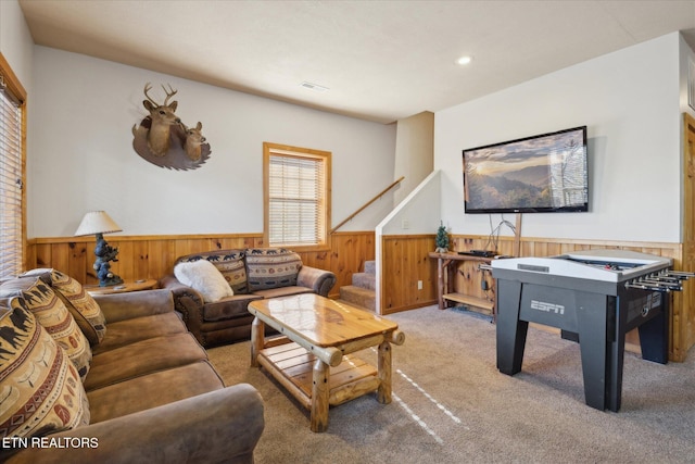 living area featuring carpet, wainscoting, wood walls, and visible vents