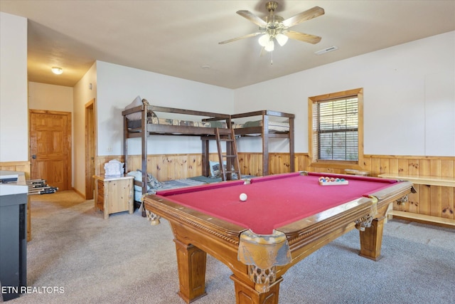 recreation room featuring wooden walls, visible vents, wainscoting, and light carpet