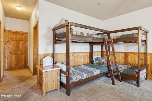 bedroom with carpet flooring, wooden walls, and wainscoting