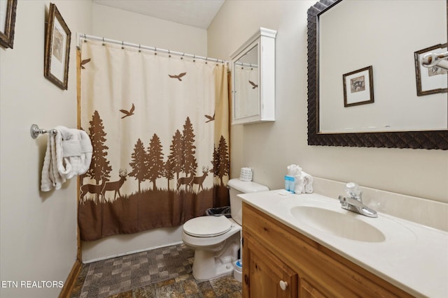 full bathroom with a shower with curtain, stone finish flooring, baseboards, vanity, and toilet