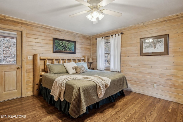 bedroom with wood walls, a ceiling fan, and wood finished floors