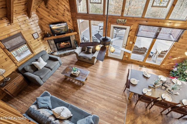 living room with wooden walls, a high ceiling, wood finished floors, and a fireplace