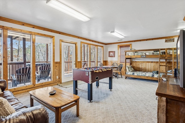 rec room with crown molding, light carpet, and a wainscoted wall