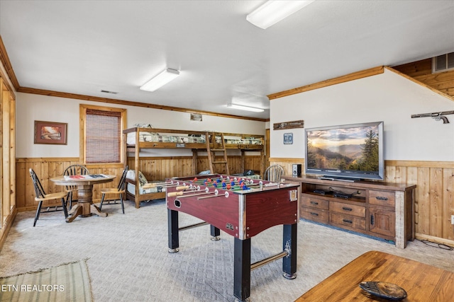 game room featuring wood walls, wainscoting, light carpet, and ornamental molding