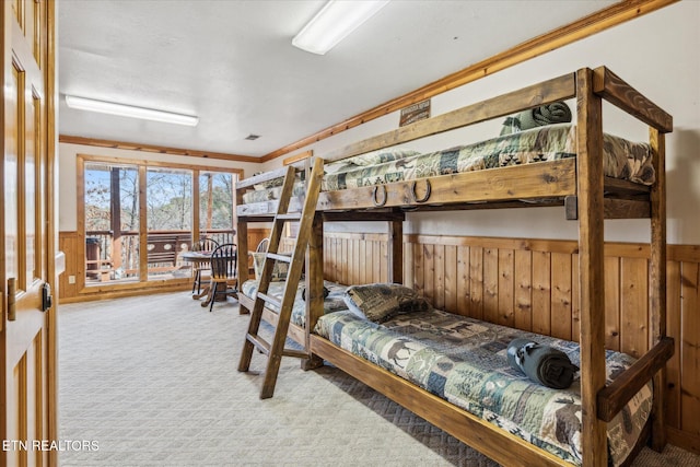 bedroom featuring carpet floors, wood walls, crown molding, and a wainscoted wall