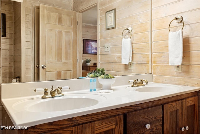 bathroom featuring a sink, wooden walls, and double vanity