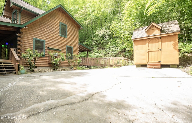 308 Black Mash Hollow Rd, Townsend, TN 37882 - view of side of property featuring a storage shed, an outbuilding, log exterior, a forest view, and roof with shingles