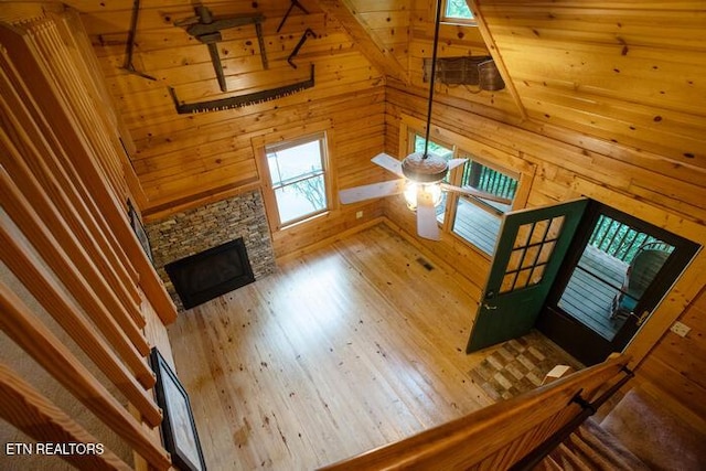 308 Black Mash Hollow Rd, Townsend, TN 37882 - unfurnished living room featuring a stone fireplace, wooden walls, wood finished floors, and ceiling fan