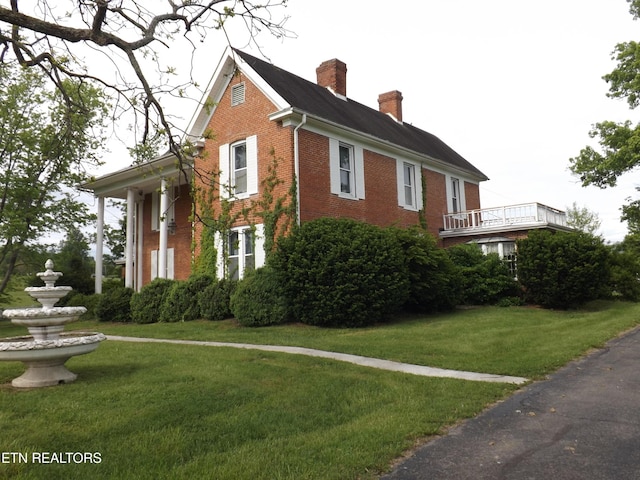 view of side of property with brick siding, a chimney, and a yard