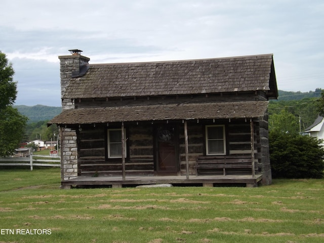 rear view of house featuring a yard and a chimney