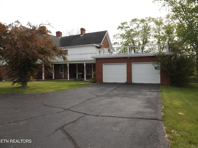 view of front of home featuring asphalt driveway, a balcony, a front lawn, brick siding, and a garage