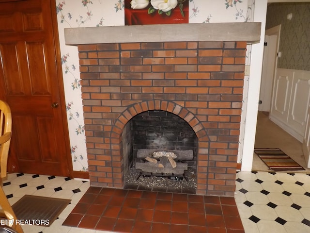 detailed view of wallpapered walls, tile patterned floors, a brick fireplace, and wainscoting