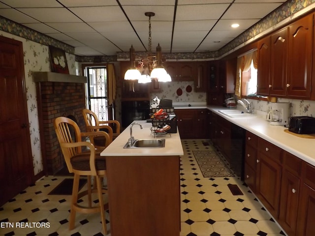 kitchen with wallpapered walls, a sink, light flooring, dishwashing machine, and a drop ceiling