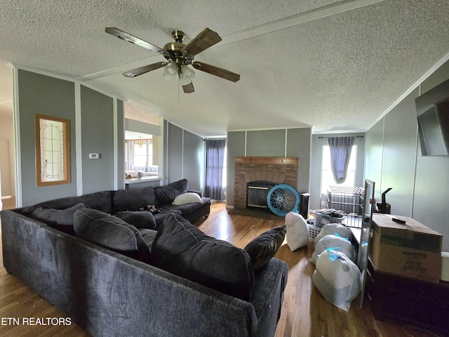 living area with a ceiling fan, a textured ceiling, wood finished floors, and a fireplace