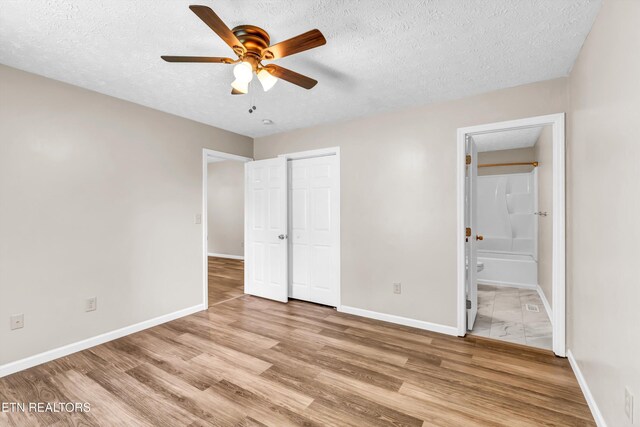 330 Ridgeview Dr, Oliver Springs, TN 37840 - unfurnished bedroom with light wood-style floors, a textured ceiling, baseboards, ensuite bathroom, and a closet