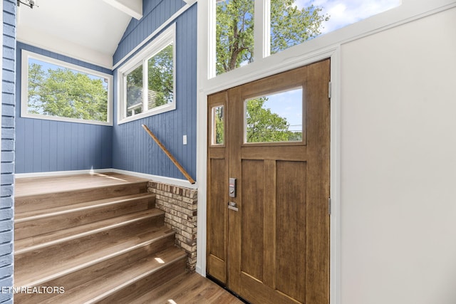 entrance foyer featuring stairs, vaulted ceiling, plenty of natural light, and wood finished floors