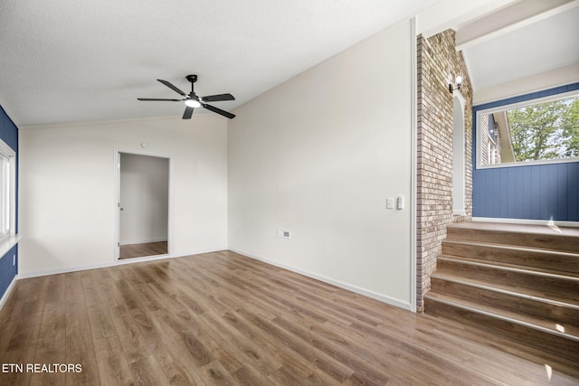 spare room with ceiling fan, vaulted ceiling, stairs, and wood finished floors