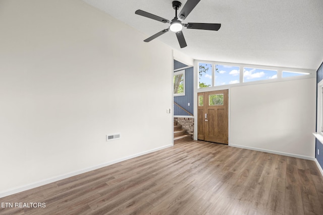 spare room featuring ceiling fan, visible vents, wood finished floors, and lofted ceiling