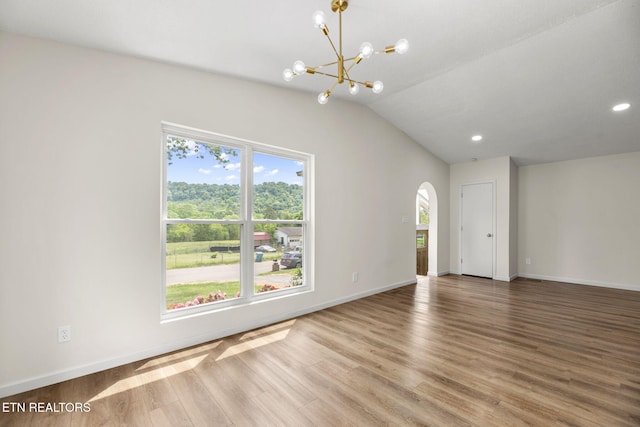 empty room with an inviting chandelier, arched walkways, baseboards, and wood finished floors