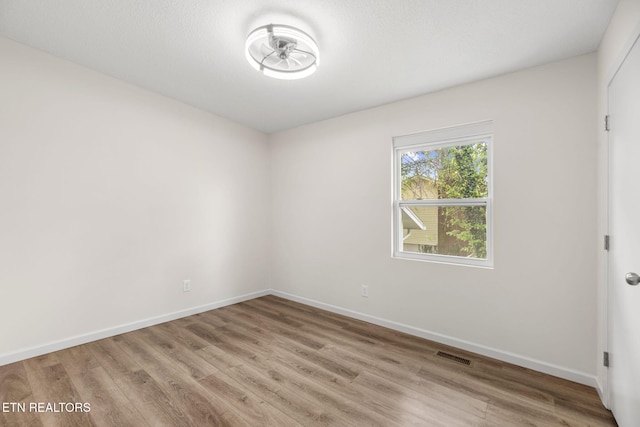 spare room with baseboards, visible vents, and light wood finished floors