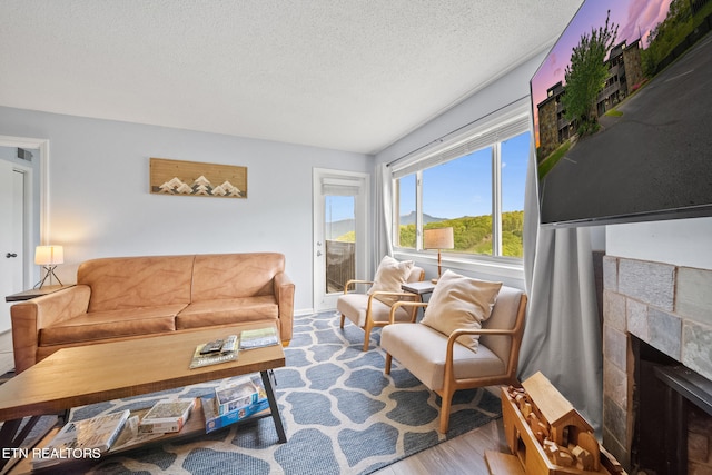 living area with a tiled fireplace, wood finished floors, and a textured ceiling