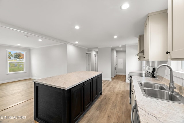 kitchen with stainless steel electric range oven, a sink, dark cabinetry, light wood-type flooring, and a kitchen island