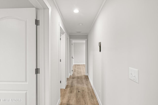 corridor featuring baseboards, ornamental molding, light wood-style flooring, and recessed lighting