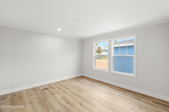empty room featuring baseboards, ornamental molding, and light wood-type flooring