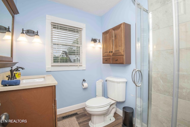 bathroom with baseboards, a stall shower, toilet, and wood finished floors