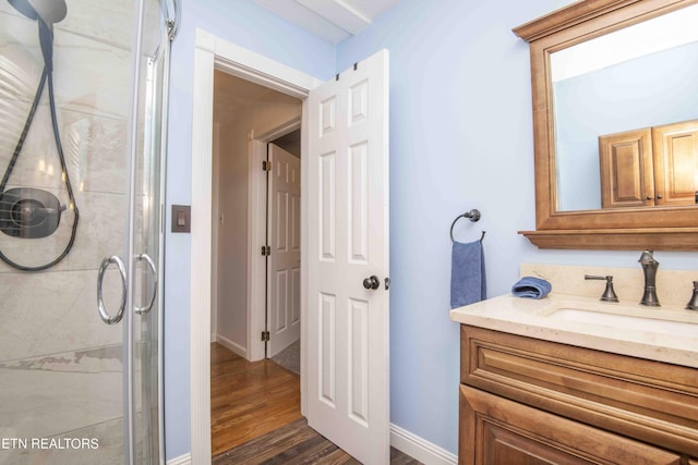 bathroom featuring vanity, baseboards, wood finished floors, and a shower stall