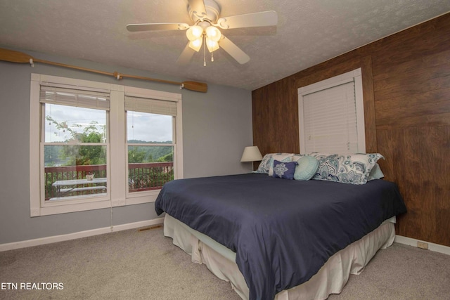 bedroom with ceiling fan, a textured ceiling, wood walls, carpet, and baseboards