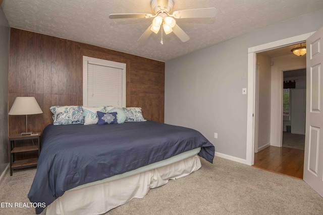 bedroom with wood walls, baseboards, a textured ceiling, a ceiling fan, and carpet