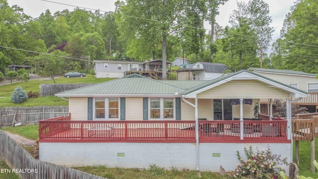 rear view of property with crawl space, fence, and metal roof