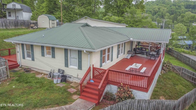 rear view of house featuring a storage unit, a fenced backyard, and a wooden deck
