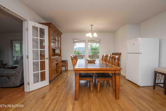dining room with baseboards, a chandelier, and light wood-style flooring