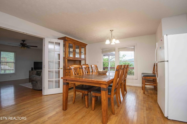 dining area with baseboards, ceiling fan with notable chandelier, and light wood-type flooring