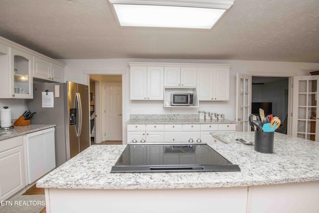kitchen featuring a kitchen island, white dishwasher, cooktop, stainless steel microwave, and glass insert cabinets