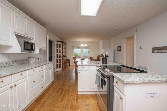 kitchen with light wood-style floors, appliances with stainless steel finishes, a textured ceiling, and visible vents