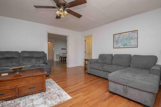 living area with light wood-style floors, a textured ceiling, ceiling fan, and visible vents