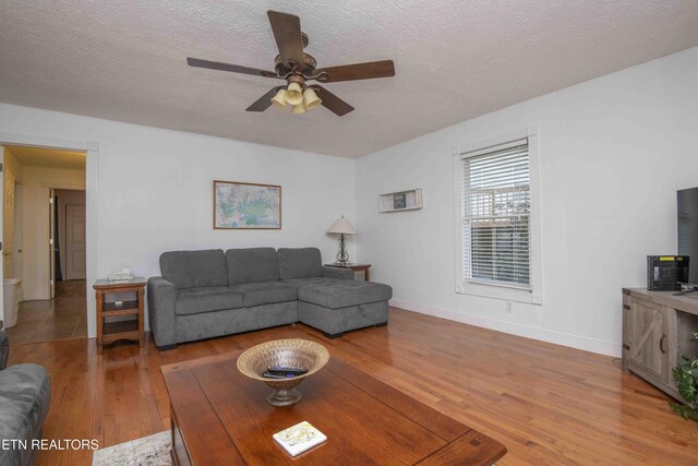 living room with baseboards, a ceiling fan, a textured ceiling, and wood finished floors