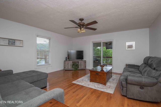 living area featuring a ceiling fan, a textured ceiling, a healthy amount of sunlight, and wood finished floors
