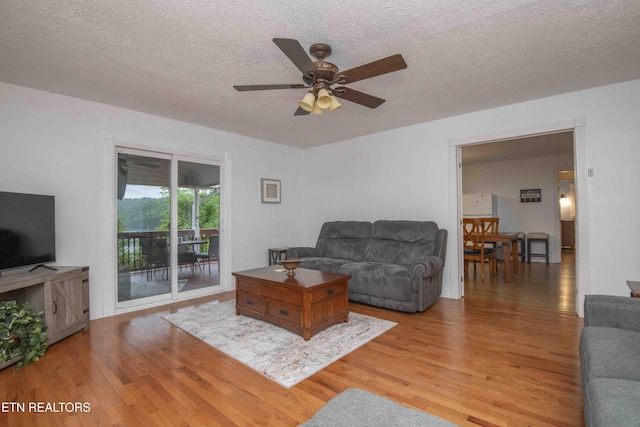 living area featuring a textured ceiling, ceiling fan, and wood finished floors