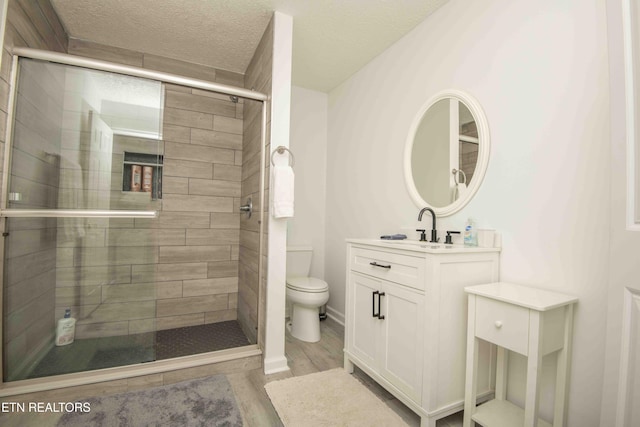full bath featuring vanity, toilet, wood finished floors, and a stall shower