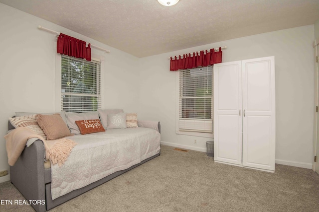 bedroom with carpet floors, a textured ceiling, visible vents, and baseboards